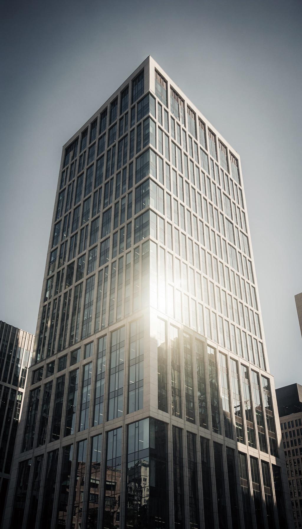 Blick von unten auf die Fassade eines modernen Bürohochhauses mit Glas und Stein