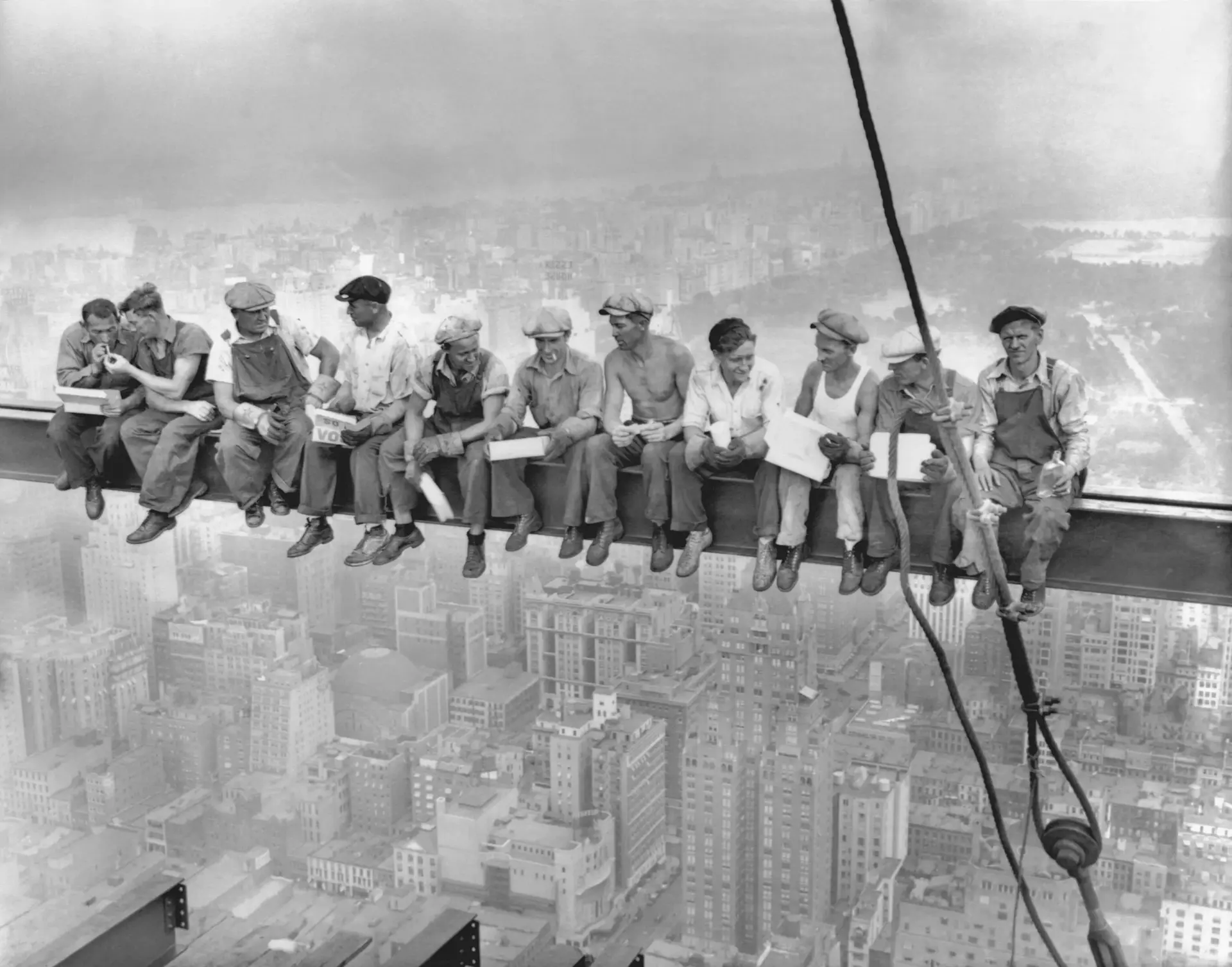 Elf Bauarbeiter sitzen auf einem Stahlträger hoch über New York City und essen während des Wolkenkratzerbaus zu Mittag.