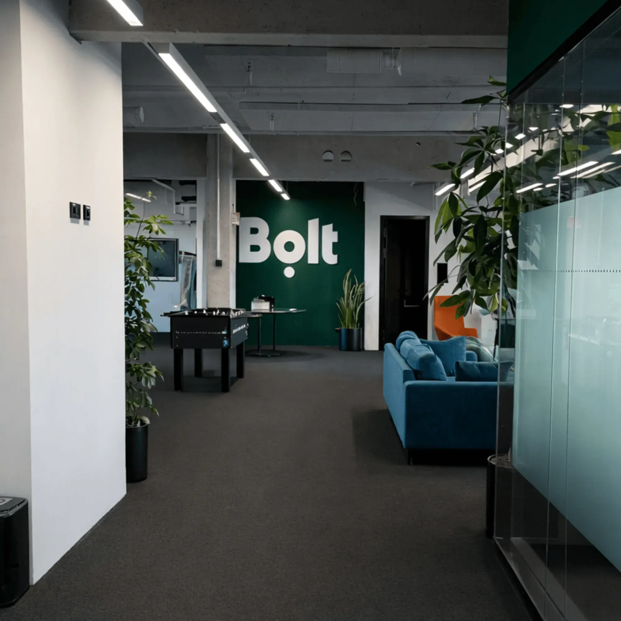 Moderner Büroflur mit Glastrennwänden und schwarzen Stahlrahmen.